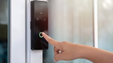 Closeup of a woman's finger entering password code on the smart digital touch screen keypad entry door lock in front of the room.