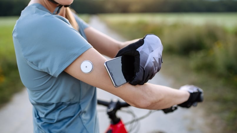Cyclist syncing glucose monitor on arm with a smartphone.