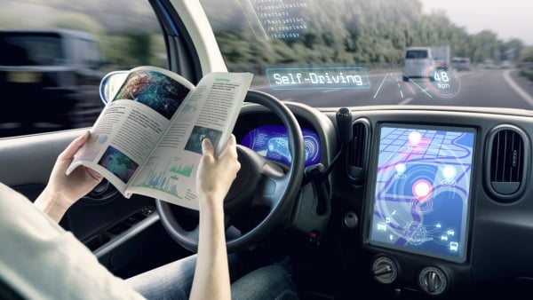 Driver reading a book in cockpit of an autonomous self-driving car.