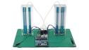 Front view of the capacitive touch liquid level indicator reference design with two transparent tanks, connecting tubes, sensors, and a CPU board and control board.