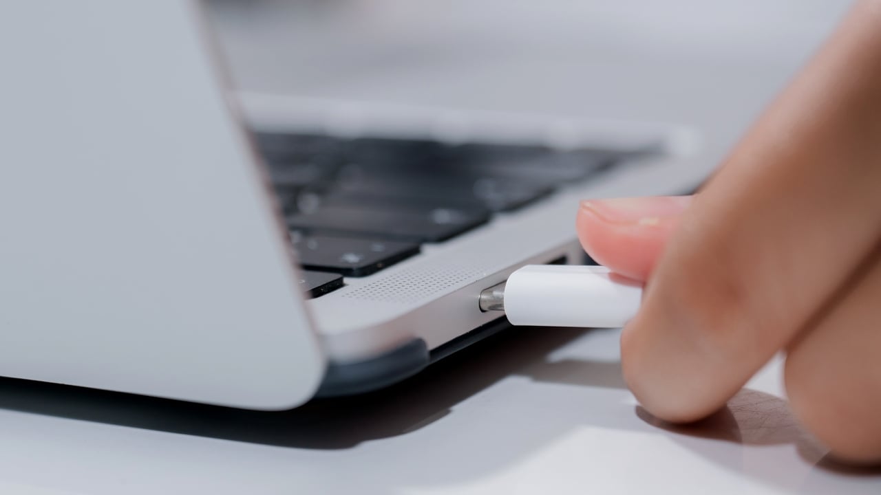 Laptop Charging Port plugged with USB Type-C Cable Person's hand about to plug ta USB Type-C cable into the laptop’s charging port.