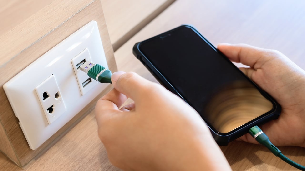 USB Socket Plugged with Phone's Charging USB Cable Person's hand is plugging a phone charger into a USB socket built into the desk.