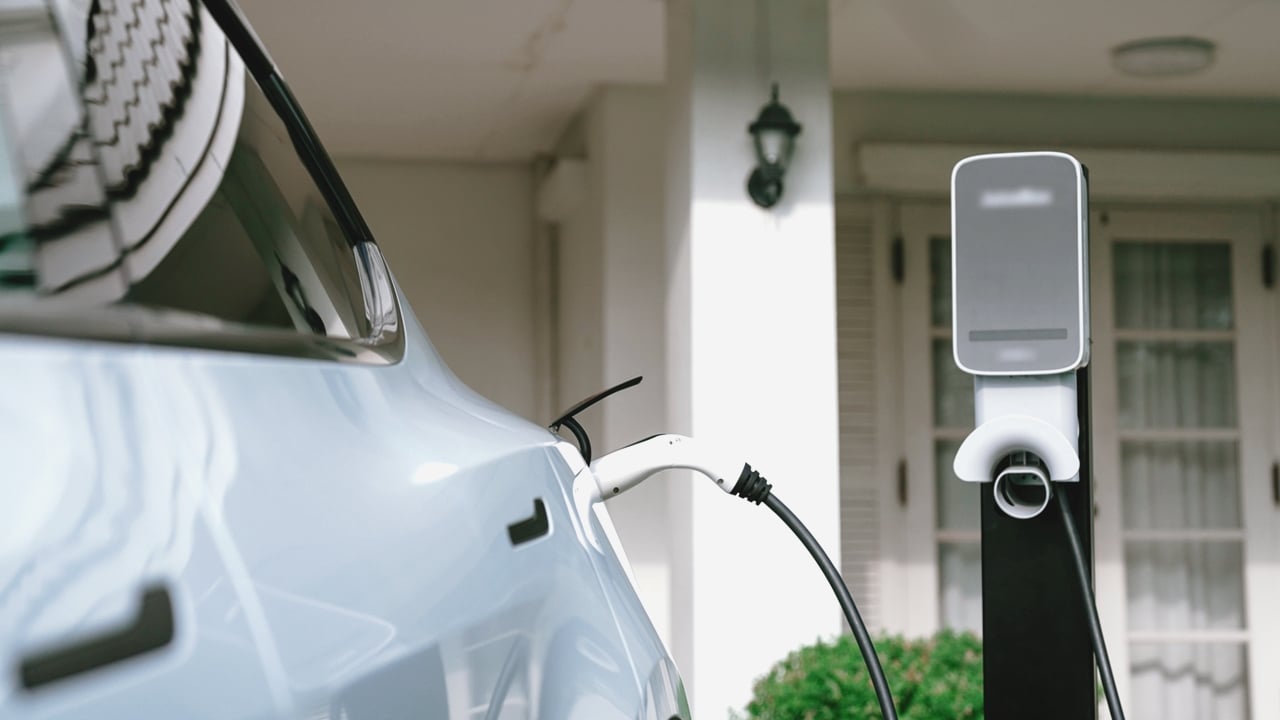 Residential EV Charging Station White electric car connected to an EV charging station outside a residential home.